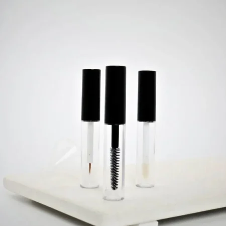 Zestaw trzech plastikowych pojemników kosmetycznych z aplikatorami.