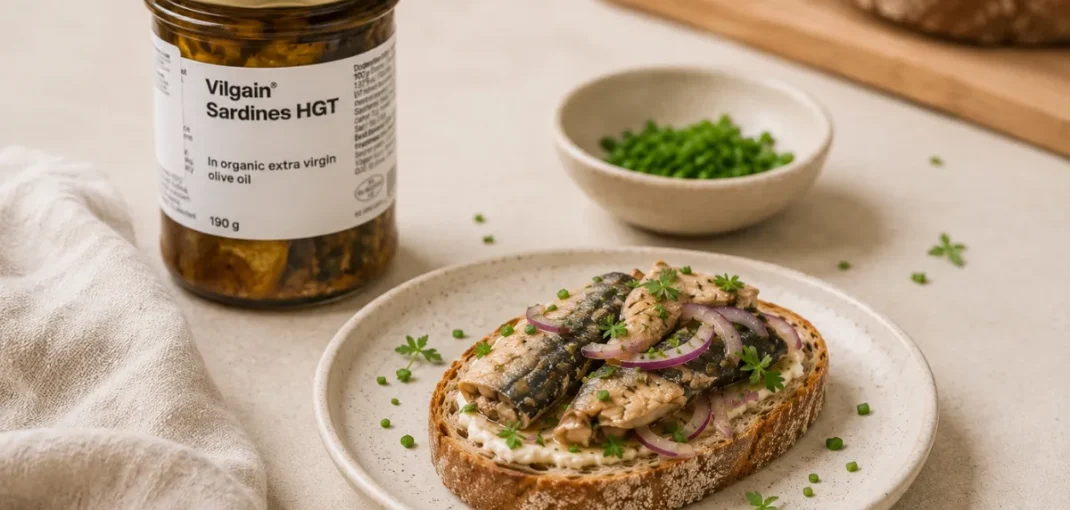 Sardynki hgt Vilgain w oliwie z oliwek extra virgin podane na pieczywie z czerwoną cebulą i szczypiorkiem.